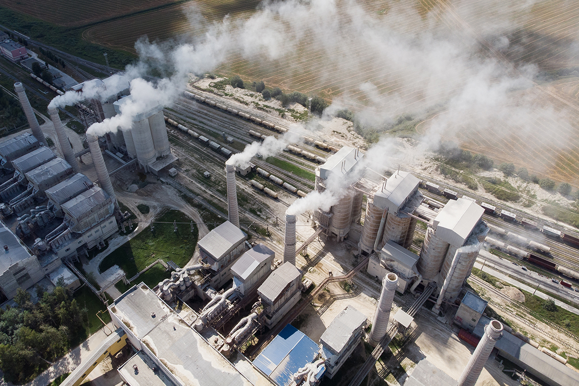 Aerial view of high chimneys of a factory with smoke rising up, polluting the atmosphere. Concept of air pollution, ecological environment. Aerial view.